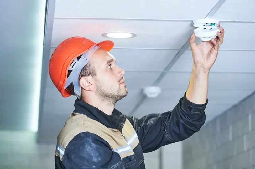 Technician servicing a ceiling smoke detector
